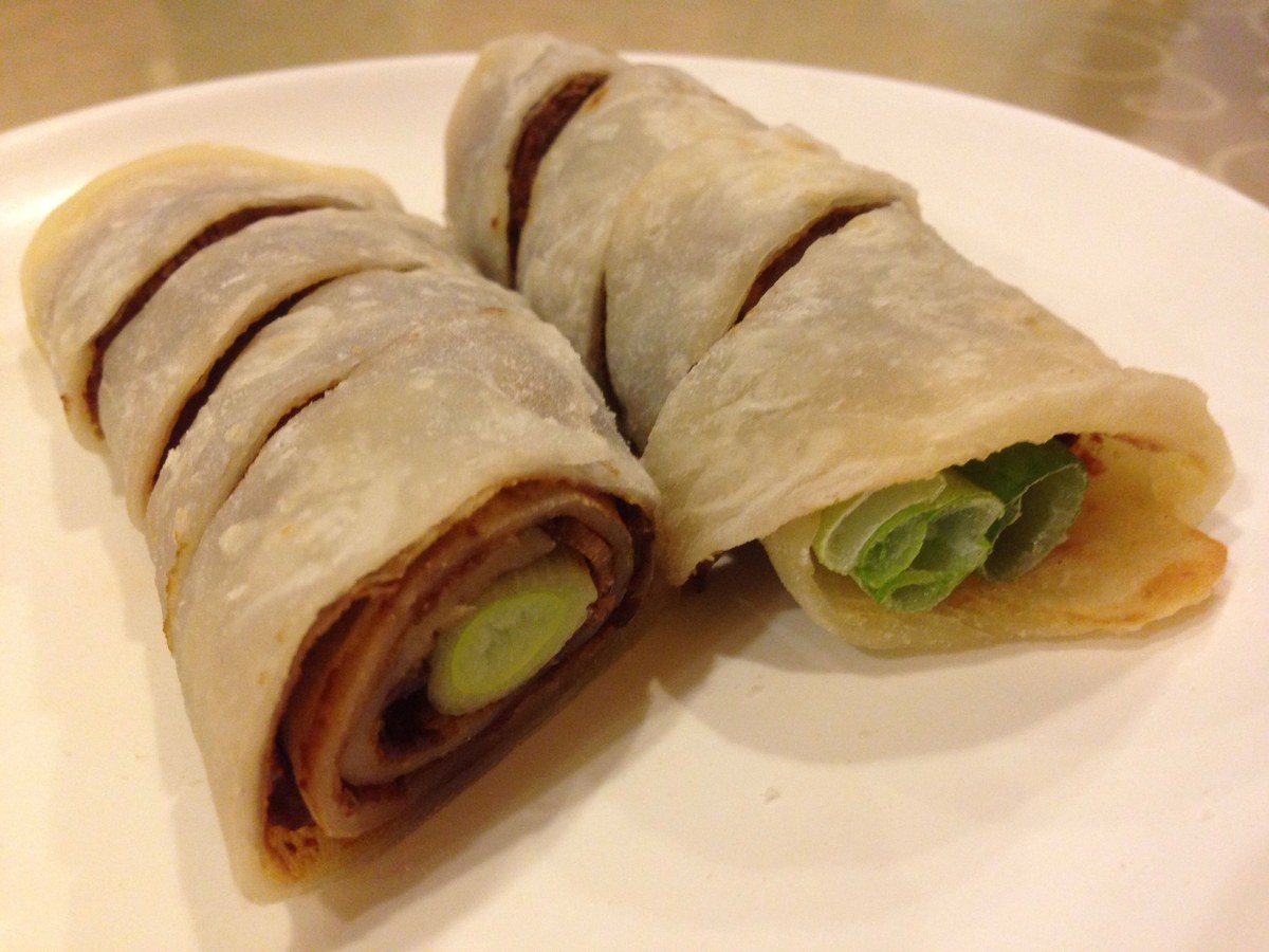 Sliced beef scallion pancake roll with cucumber and green onion filling.