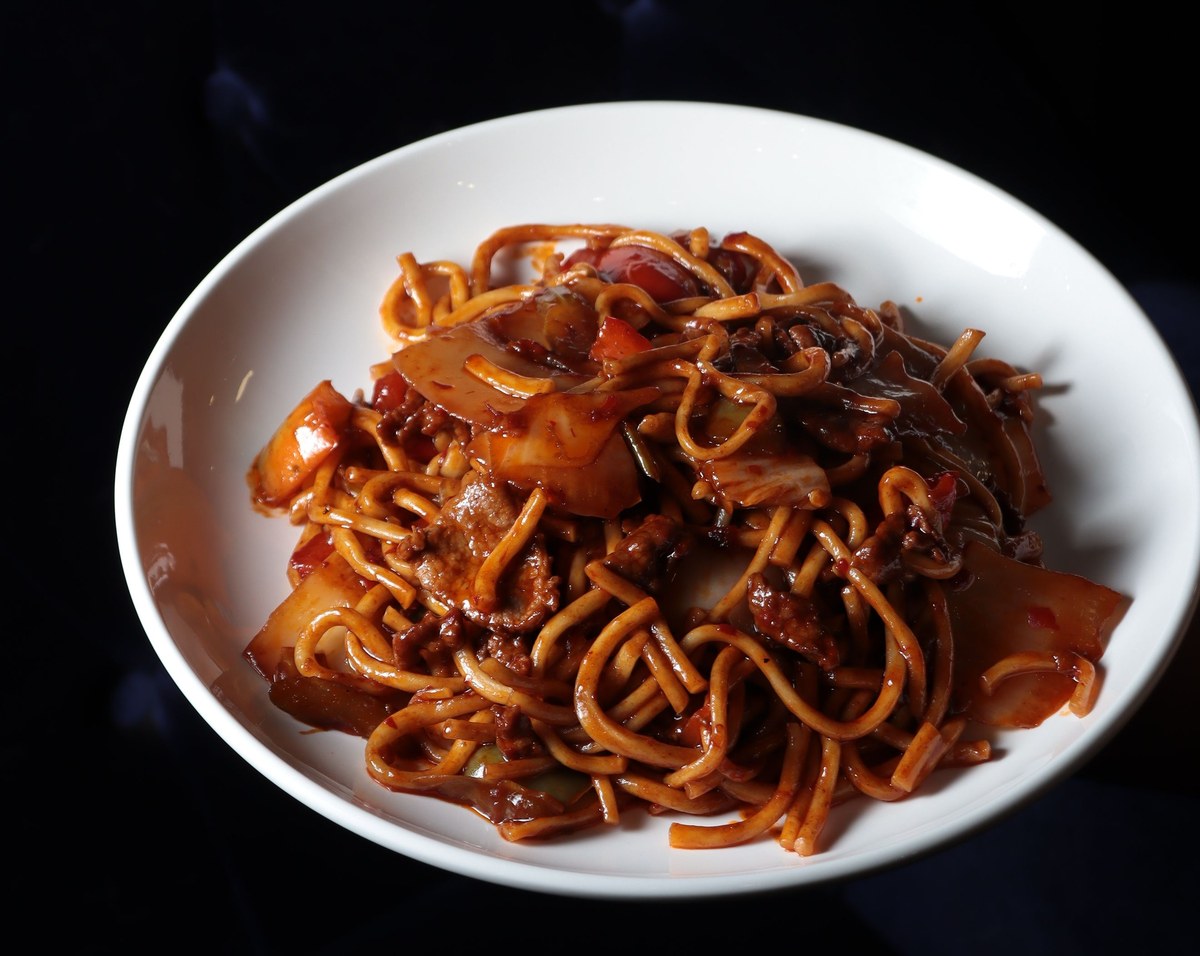 Braised bamboo shoot noodles with glossy soy sauce and sliced toppings in a white bowl.