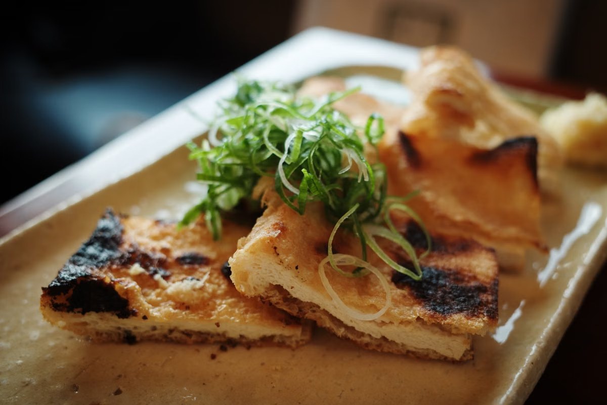 Scallion tofu with seared tofu pieces and sliced green scallions on top.