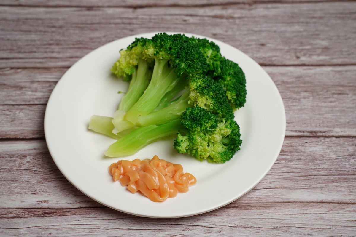 Broccoli with garlic sauce on a white plate with crisp green florets.