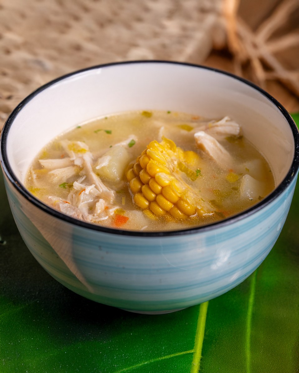 Chinese chicken corn soup with sweet corn, egg ribbons, and tender chicken in a blue bowl.