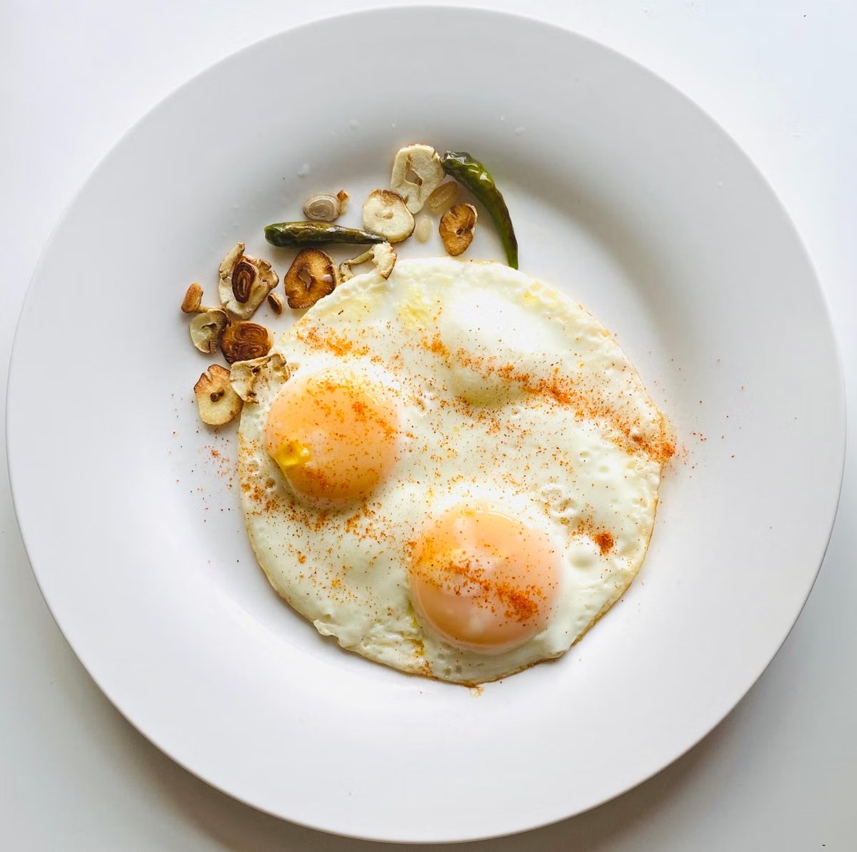 Chili oil fried eggs with crisp whites, garlic, spices, and green chile.