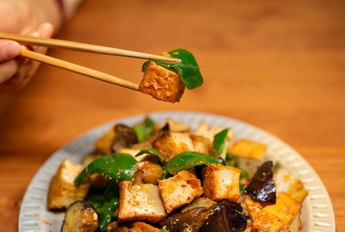 Tofu stir-fry with vegetables in a glossy chili garlic sauce on a serving plate.