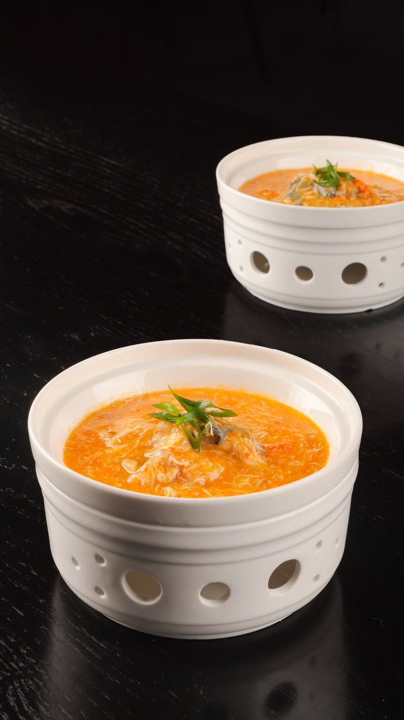 Crab egg drop soup with orange broth, crab meat, and silky egg ribbons.