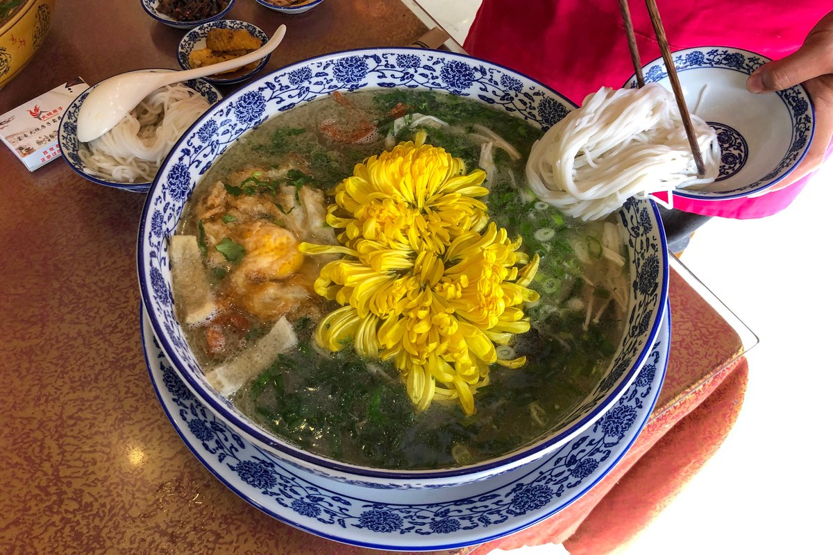 Crossing bridge rice noodles with hot broth, rice noodles, and separate toppings.