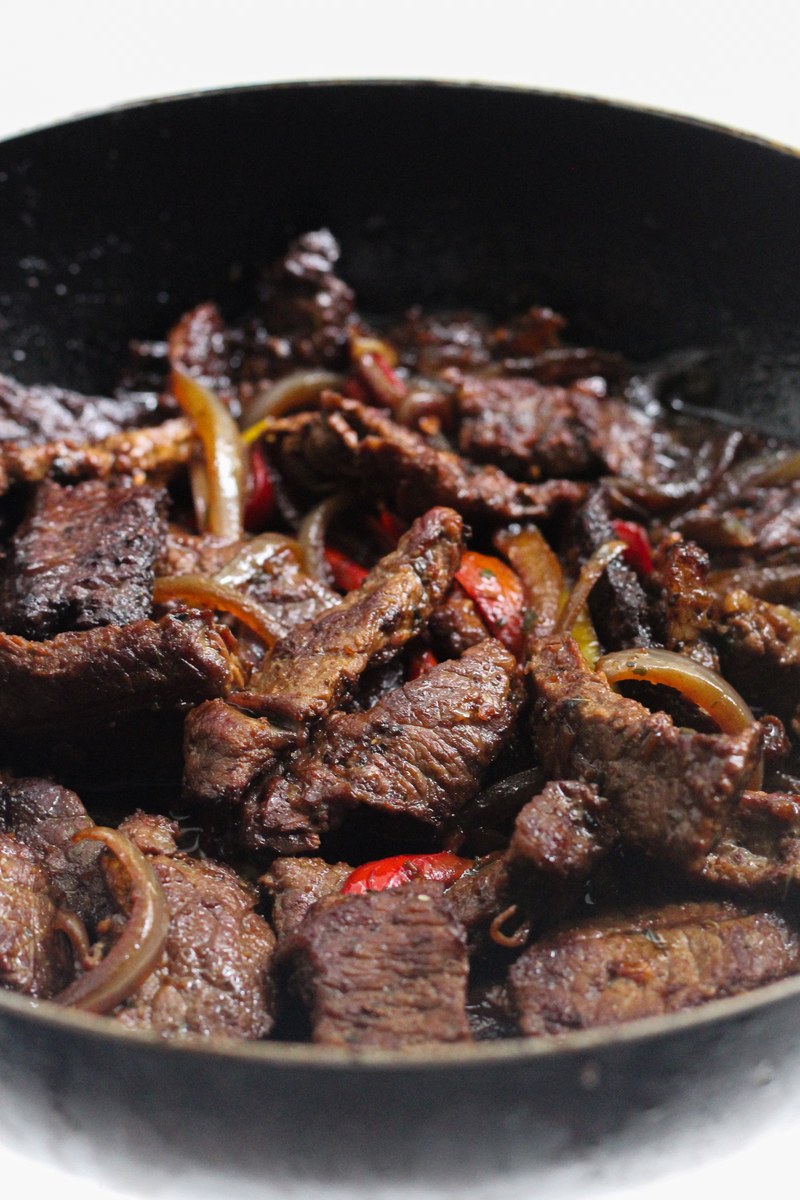 Cumin beef stir-fry with sliced beef strips and onions in a hot pan.