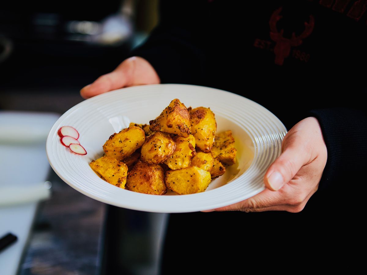 Golden potato chunks with red spice and herbs on a white plate for cumin potatoes.