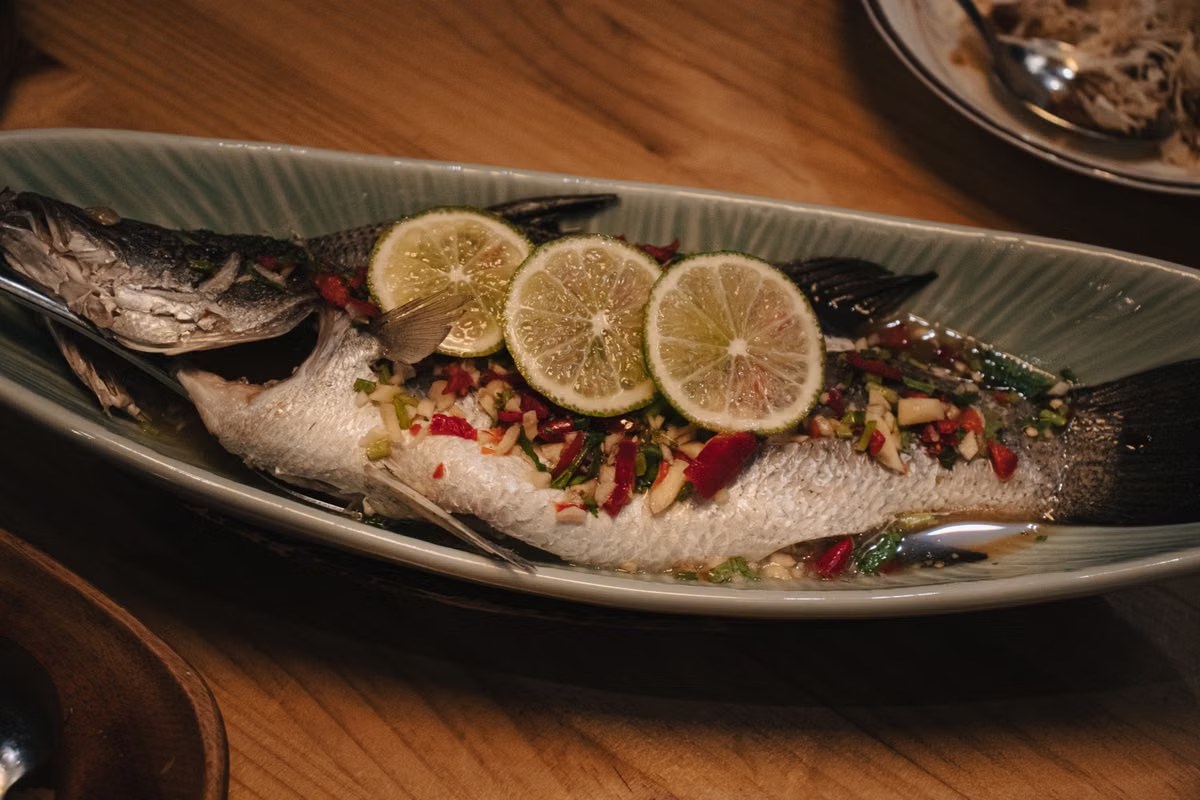 Dai-style lime chili steamed whole fish with ginger, herbs, and lime slices.
