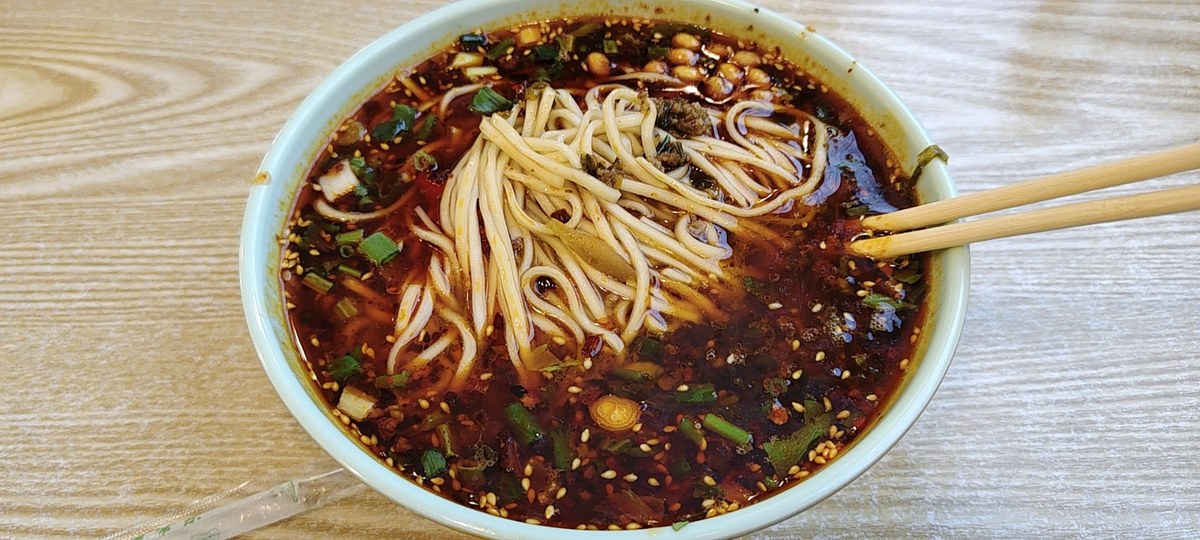 Dan dan noodles with chili oil, sesame sauce, minced pork, scallions, and greens.