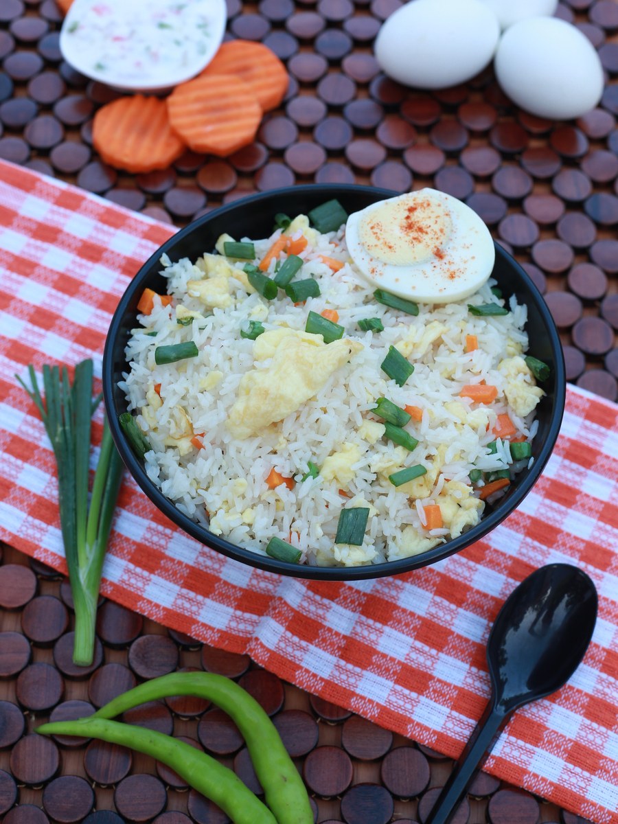 Egg fried rice with separate grains, egg pieces, vegetables, and scallions.