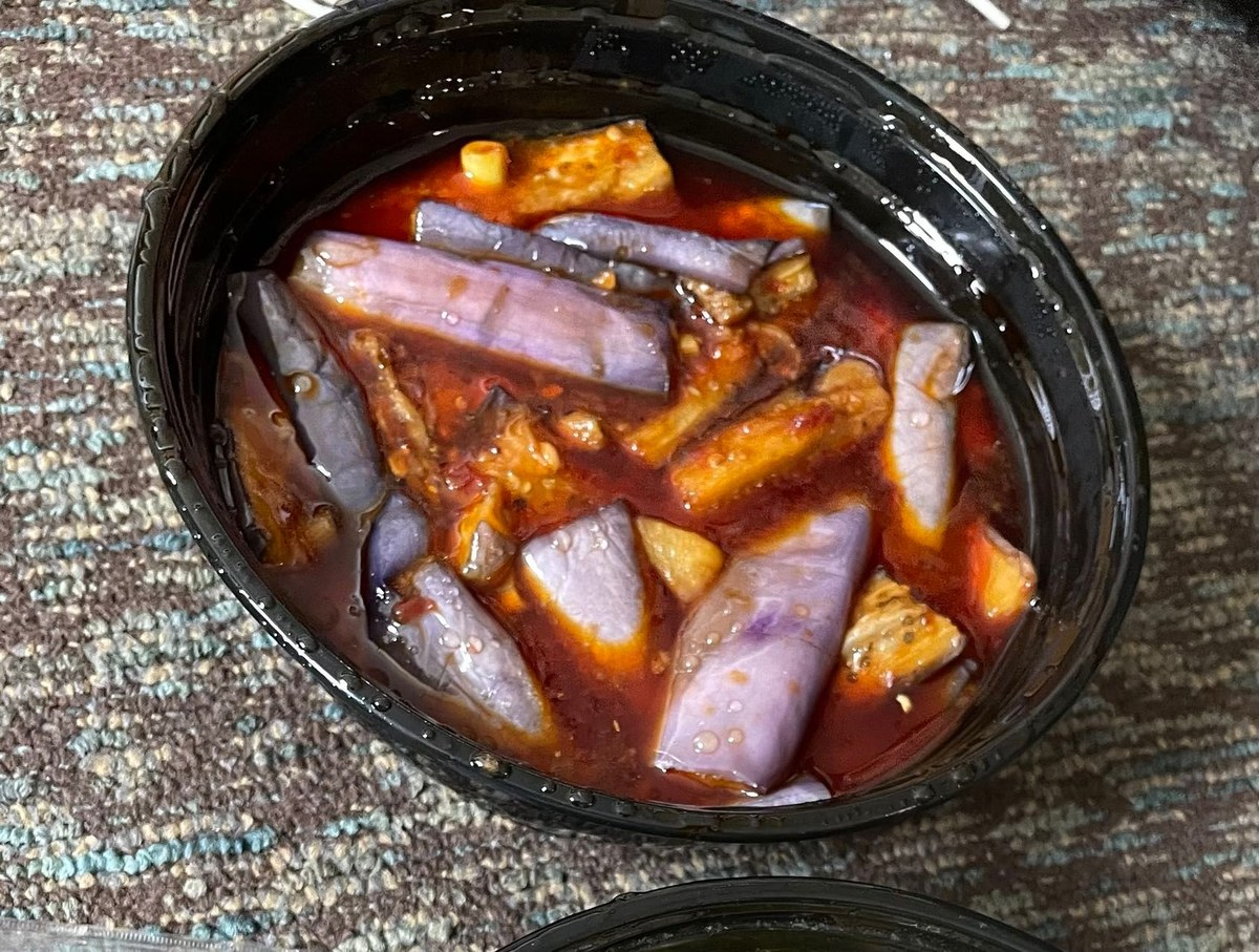 Chinese eggplant in garlic chili sauce on a white plate with red oil