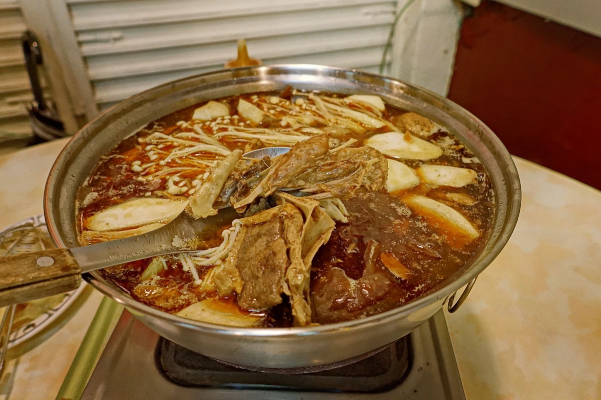 Ginger duck hot pot with duck pieces, mushrooms, and a sesame oil rice wine broth.