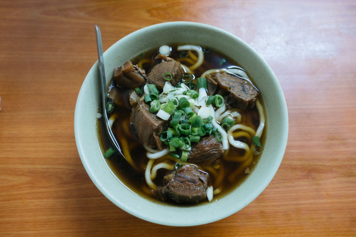 Taiwanese beef noodle soup with braised beef chunks, wheat noodles, dark broth, and scallions.