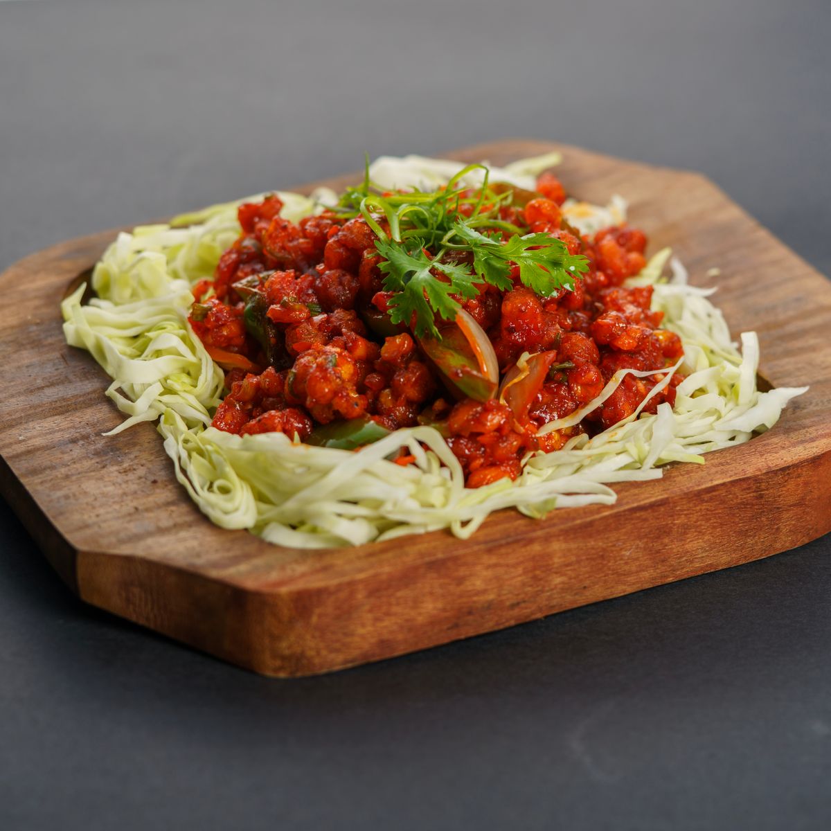 Garlic chili cauliflower bites in a sticky red-brown glaze with fresh garnish.
