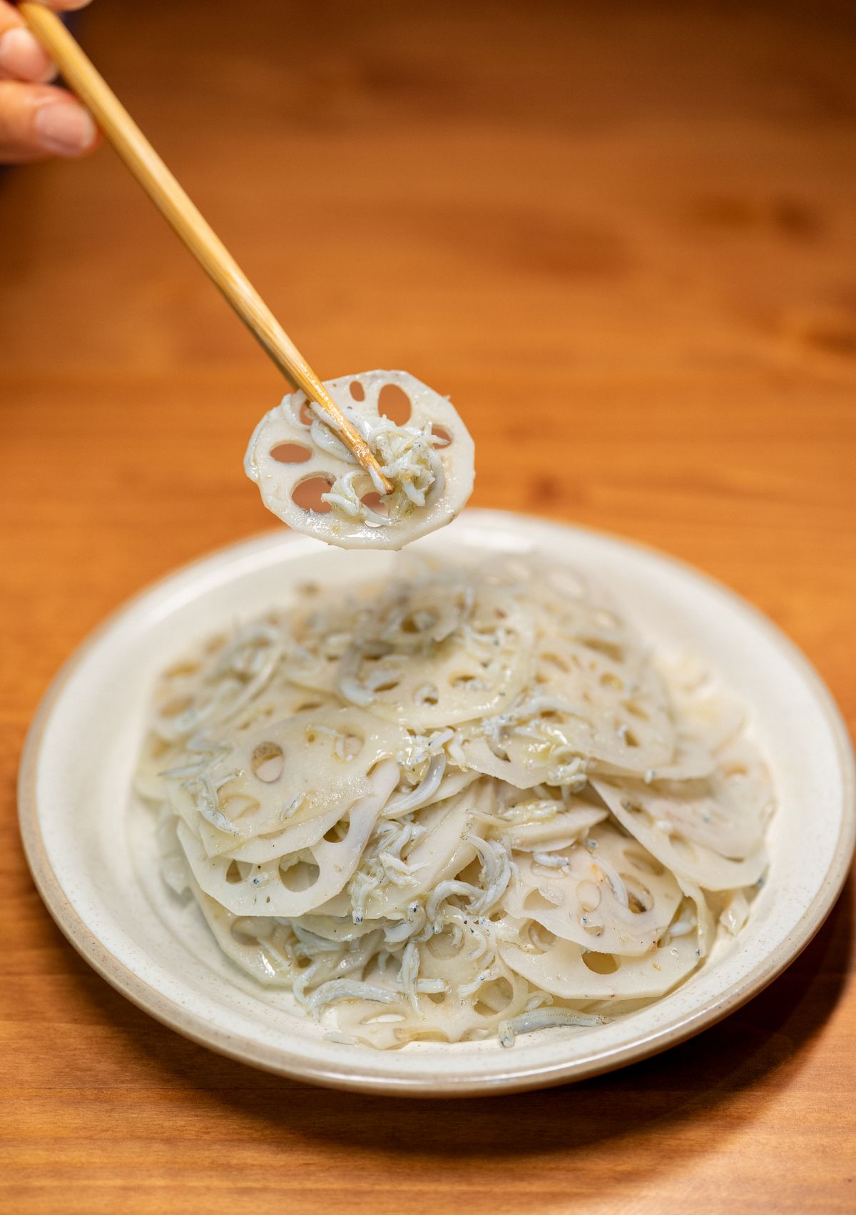 Lotus root salad with sliced lotus root and tiny dried seafood in a pale vinegar dressing.