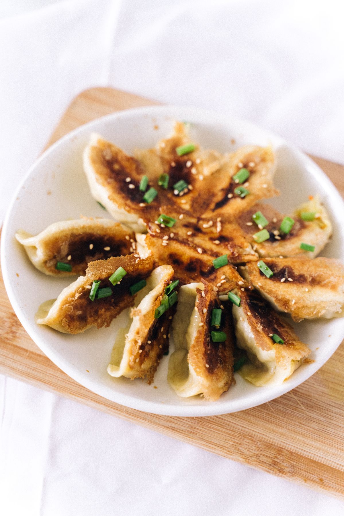 Crispy pan-fried dumplings with browned bottoms, scallions, and sesame seeds.