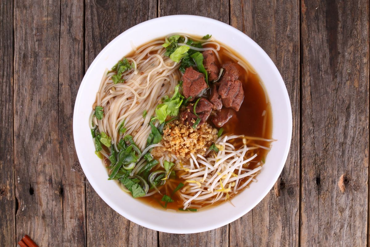 Chinese beef rice noodle soup with sliced beef, rice noodles, bean sprouts, greens, and broth.