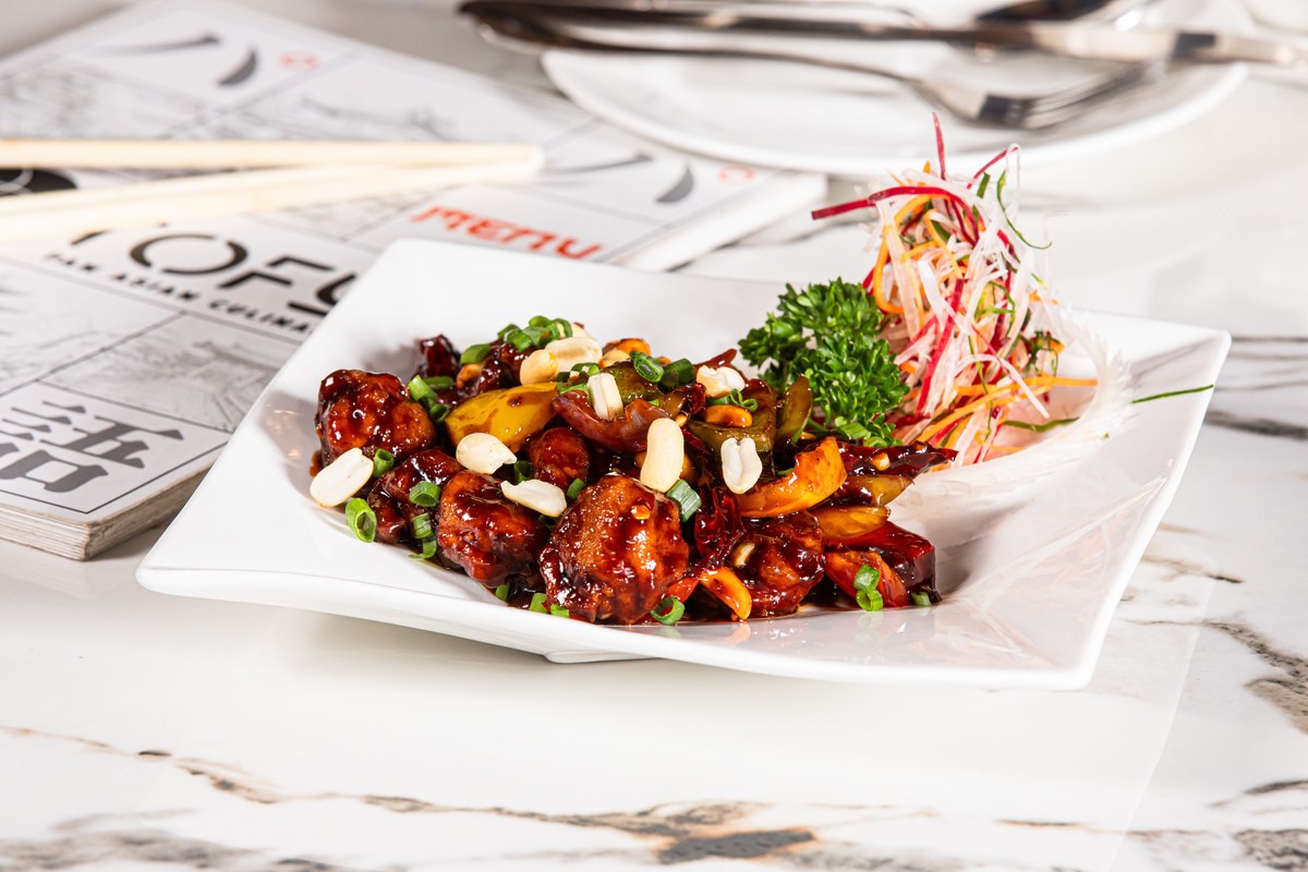 Kung pao chicken with peanuts, dried chilies, and glossy sauce on a white plate.
