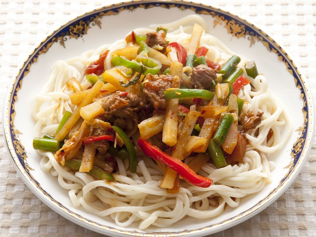 Xinjiang laghman noodles topped with lamb, peppers, tomato sauce, and scallions.