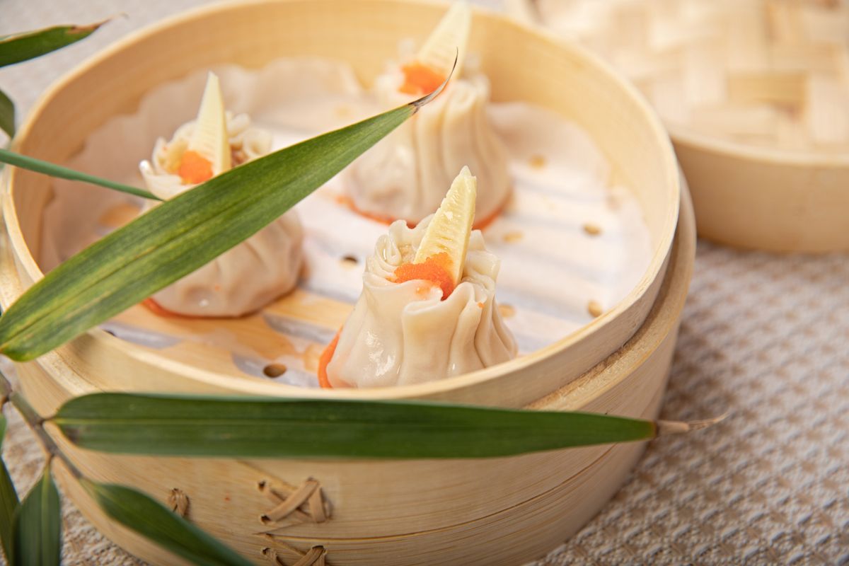 Open-top pork and shrimp siu mai dumplings in a bamboo steamer.