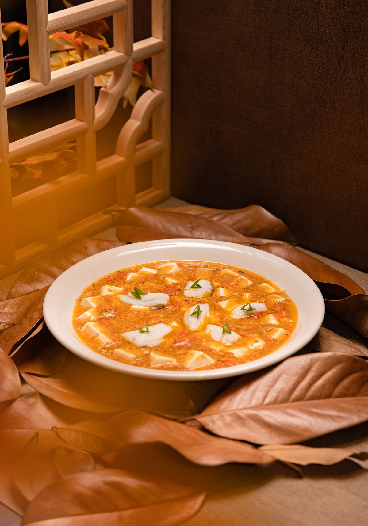 Hot and sour tofu soup with tofu cubes, egg ribbons, chili oil, and scallions.