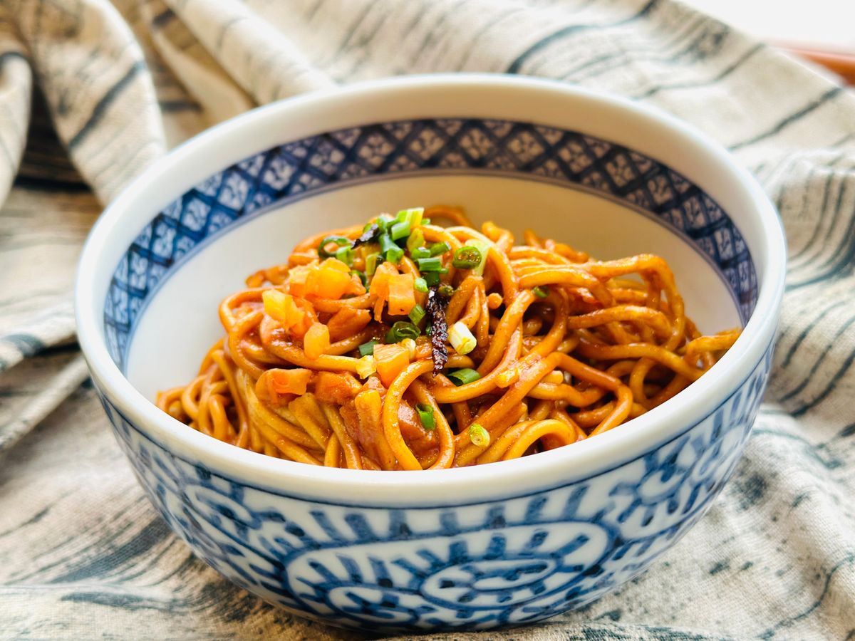 Chili garlic noodles with vegetables and glossy sauce in a bowl.