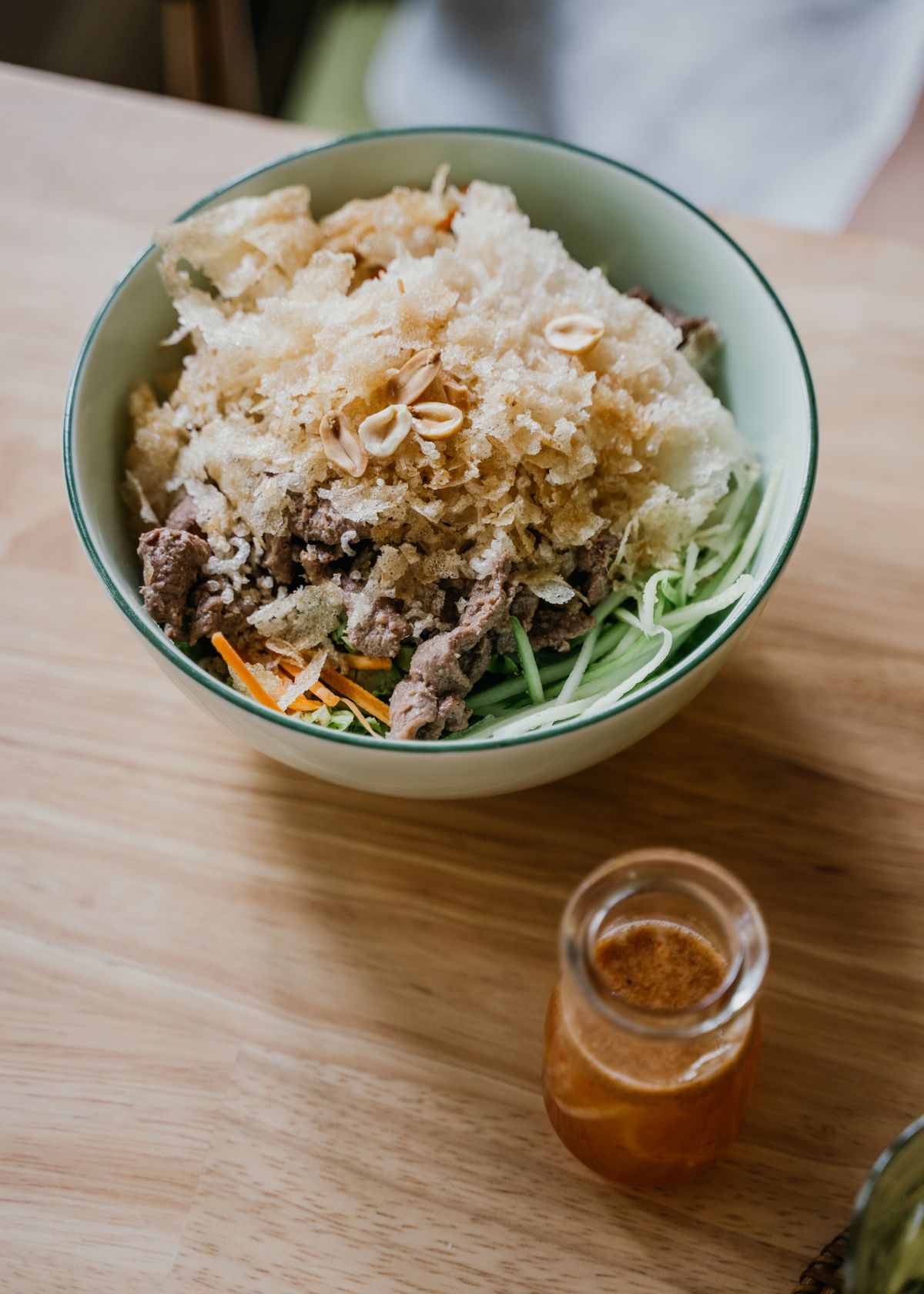 Chinese crispy beef noodle salad with sliced beef, shredded greens, peanuts, dressing, and crunchy topping.