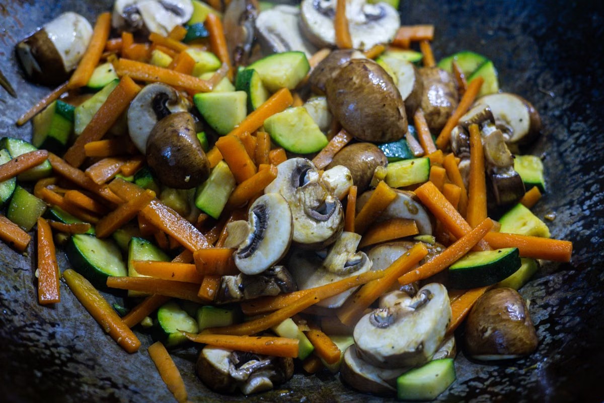 Mushroom zucchini stir-fry with carrots cooking in a wok.
