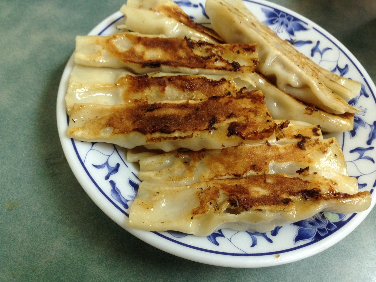 Guo tie pan-fried pork dumplings with golden browned bottoms on a plate.