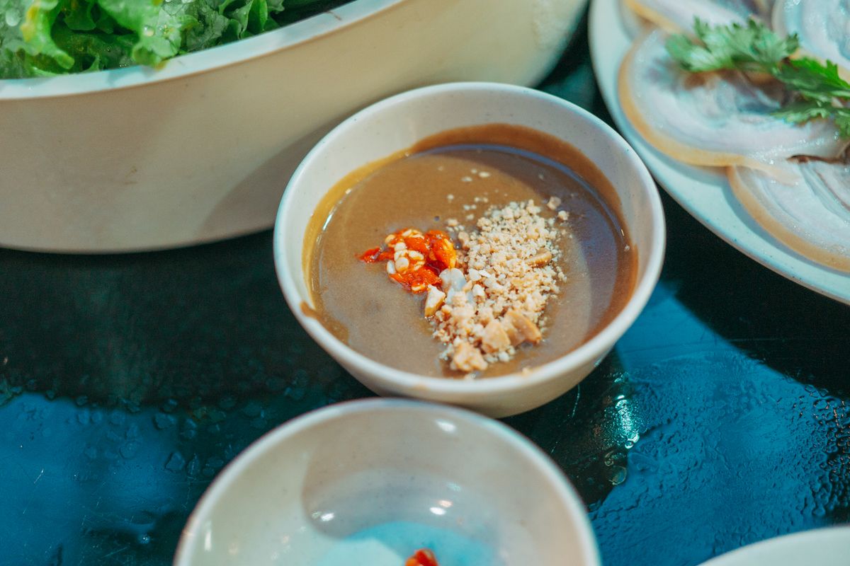 Beijing hot pot peanut sesame dipping sauce with crushed peanuts and chili oil in a small bowl.