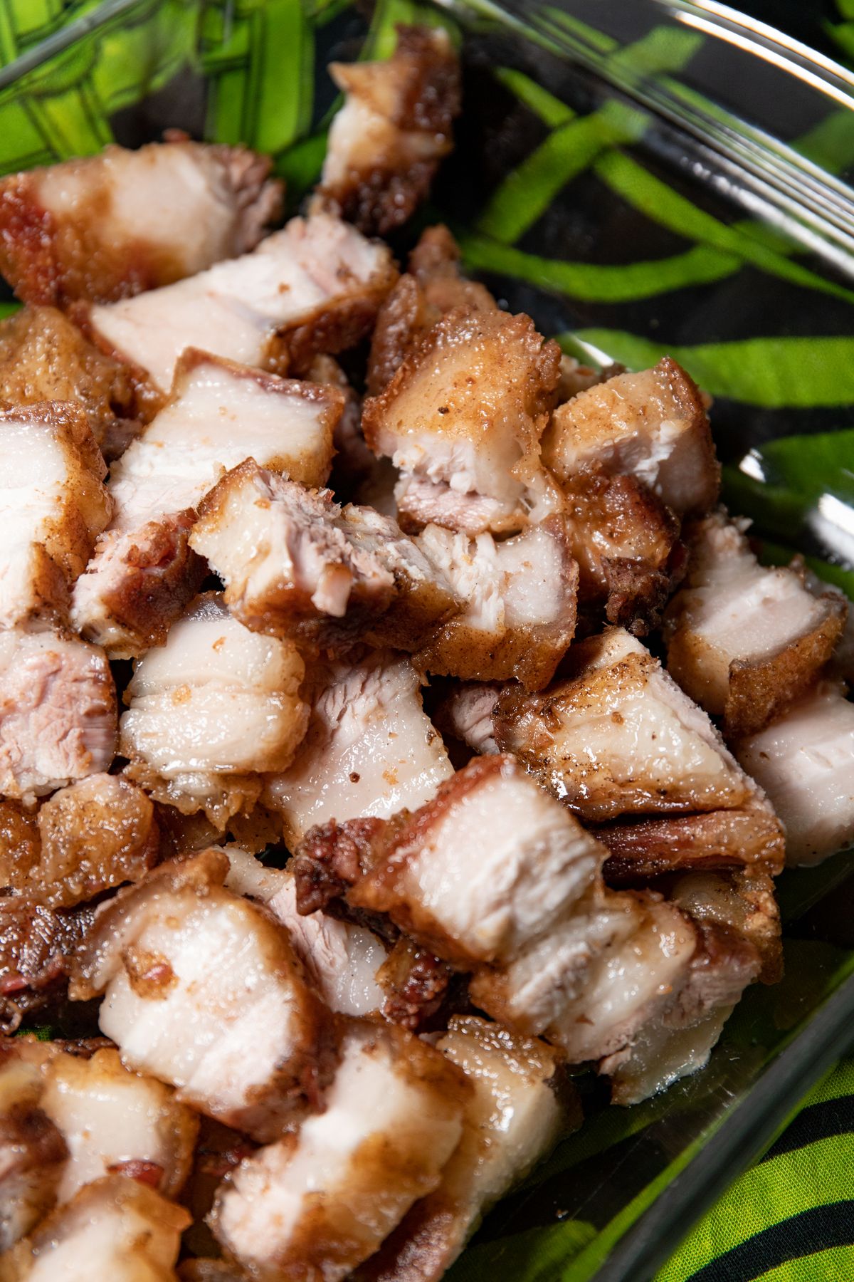Crispy pork belly pieces served with fresh green leaves for lettuce wraps.