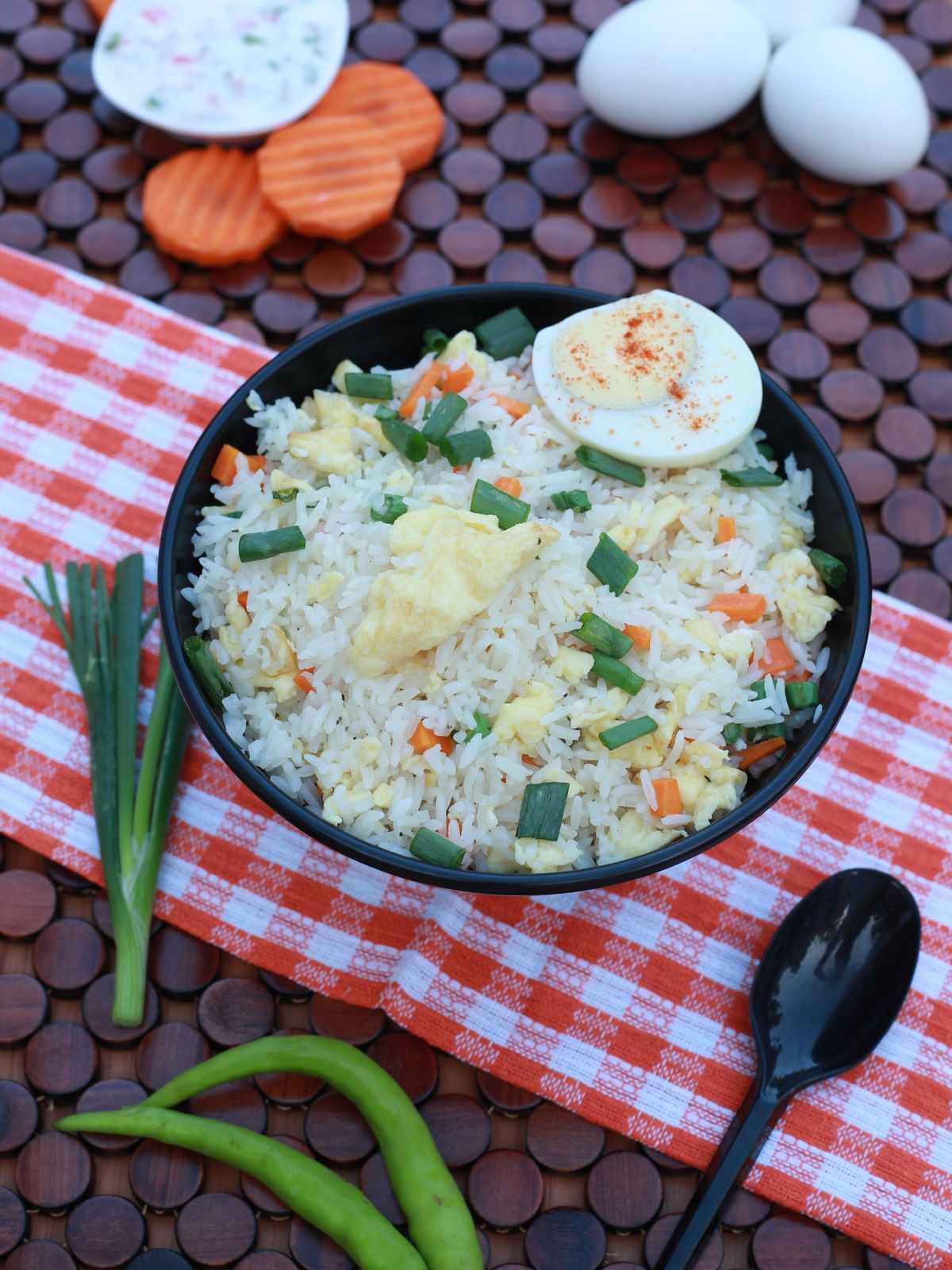 Scallion egg fried rice with loose grains, egg curds, chopped scallions, carrot, and boiled egg garnish.