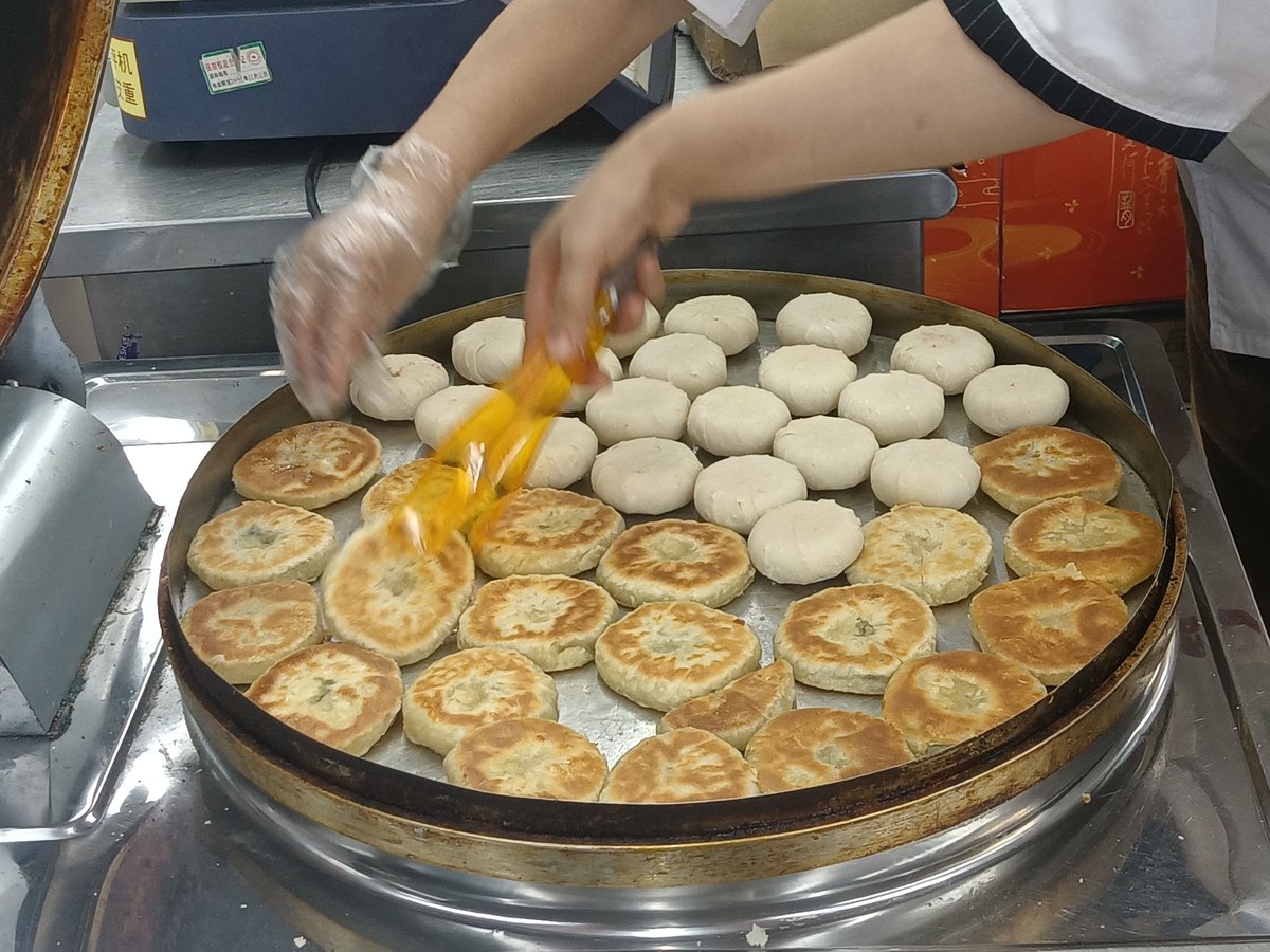 Chinese scallion pancakes cooked on a flat griddle with crisp layered edges.