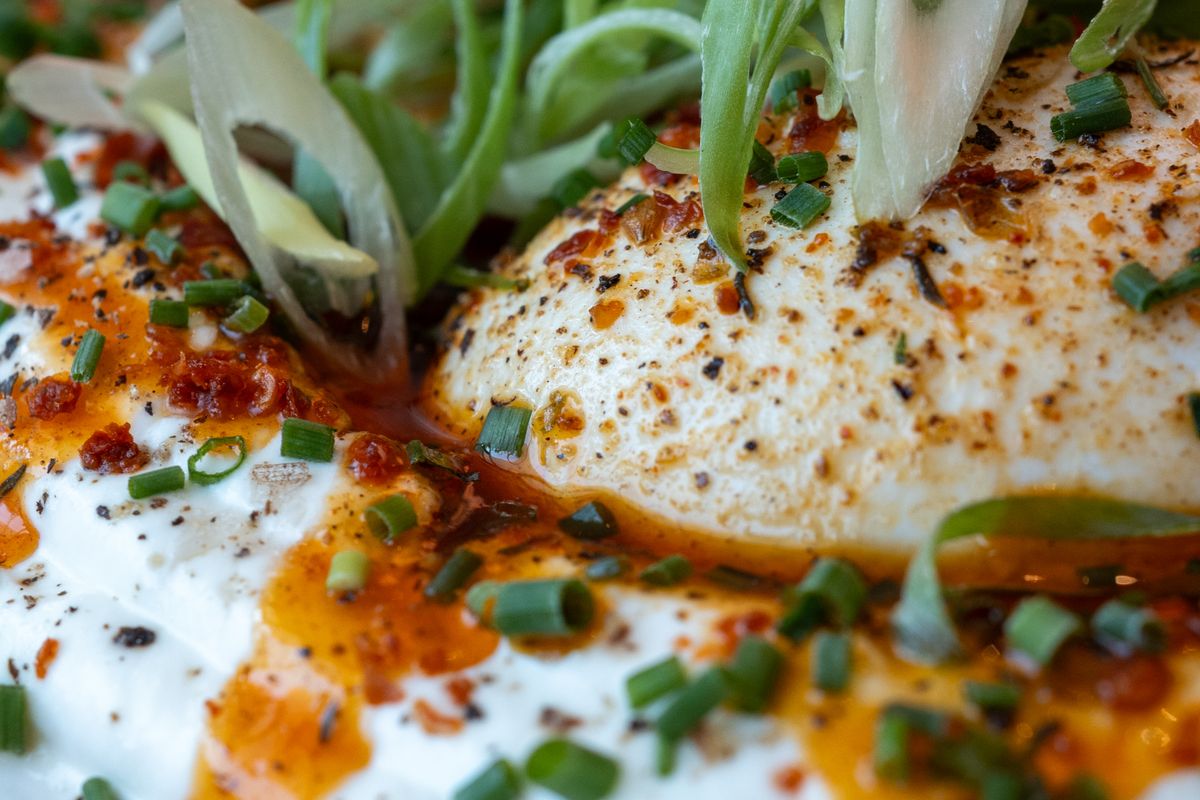 Fried eggs with chili oil, scallions, and pepper in a close-up pan-style view.
