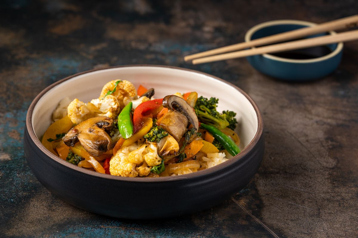 Vegetable rice bowl with mushrooms, cauliflower, broccoli, bell pepper, snap peas, and rice.