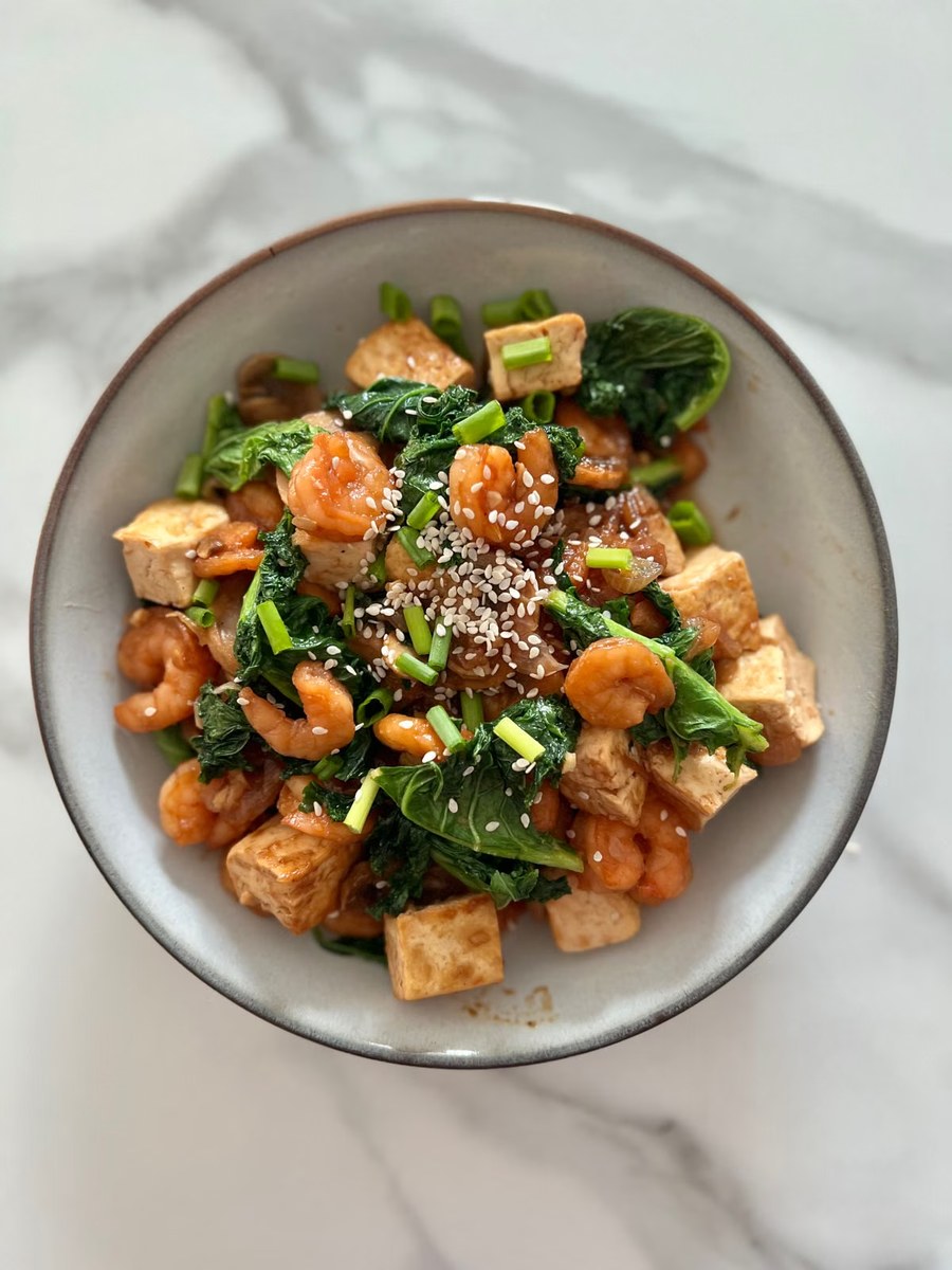 Shrimp and tofu stir-fry with leafy greens, scallions, and sesame.