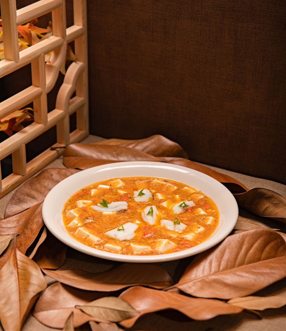 Tomato tofu fish soup with white fish slices, soft tofu cubes, scallions, and orange tomato broth.