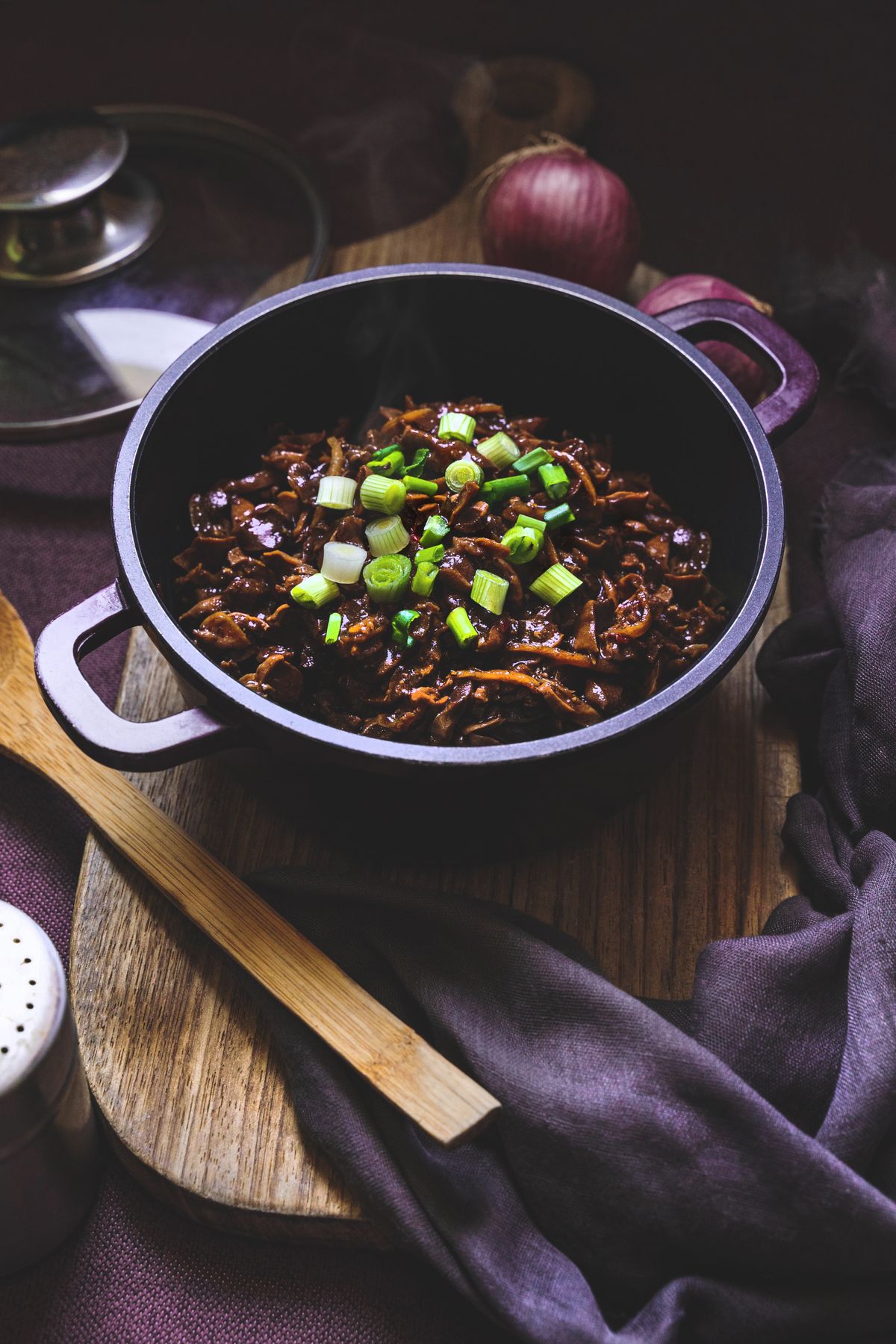 Soy-braised shredded mushrooms in a dark glossy sauce topped with chopped scallions.