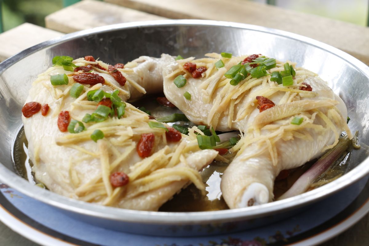 Ginger goji steamed chicken quarters with scallions, ginger threads, goji berries, and clear pan broth.