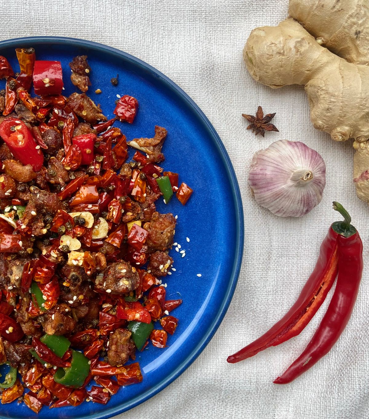 Dry chili pork belly stir-fry with dried red chilies, garlic, ginger, green chili, sesame, and Sichuan peppercorn.