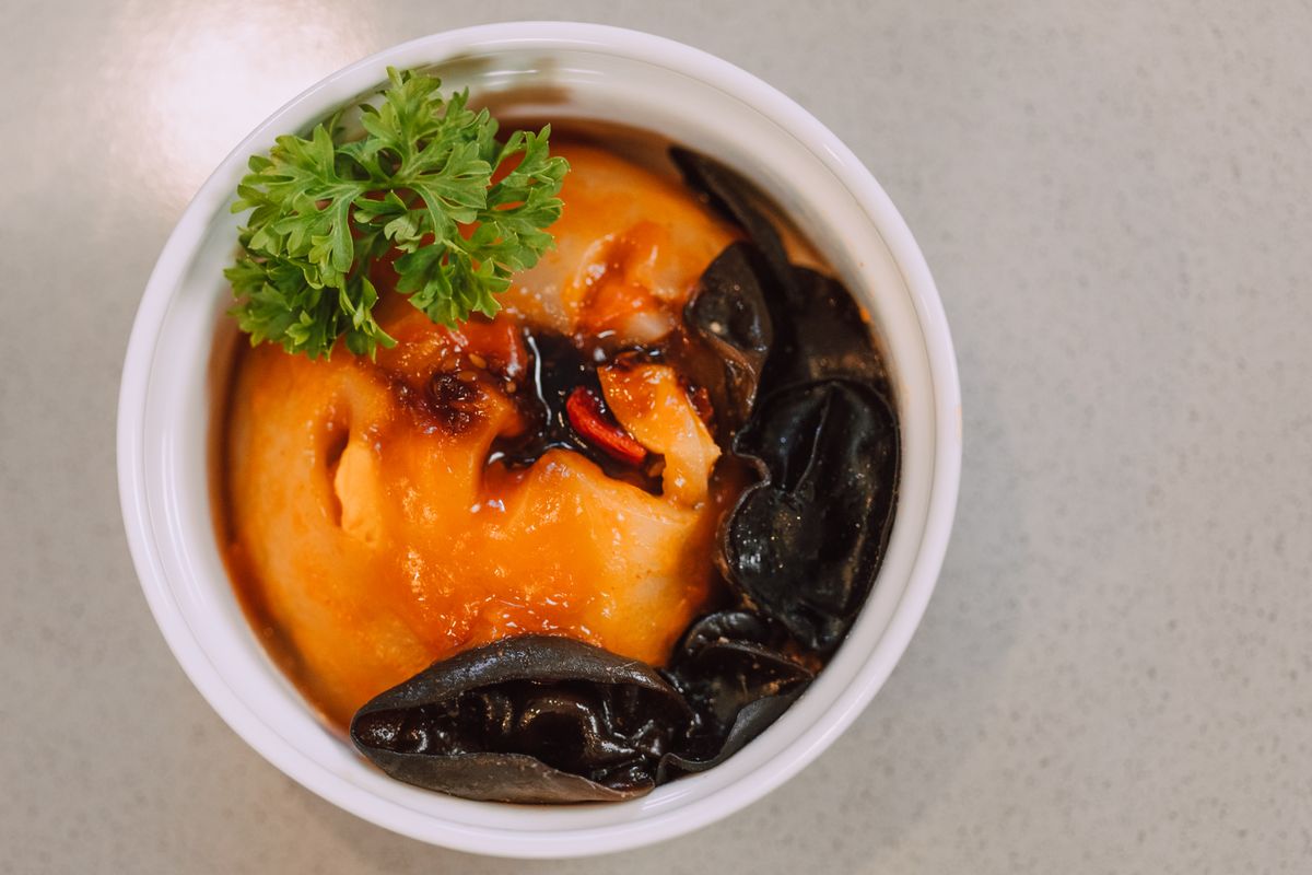 Steamed egg custard with wood ear mushrooms, chili oil, and a small green herb garnish.