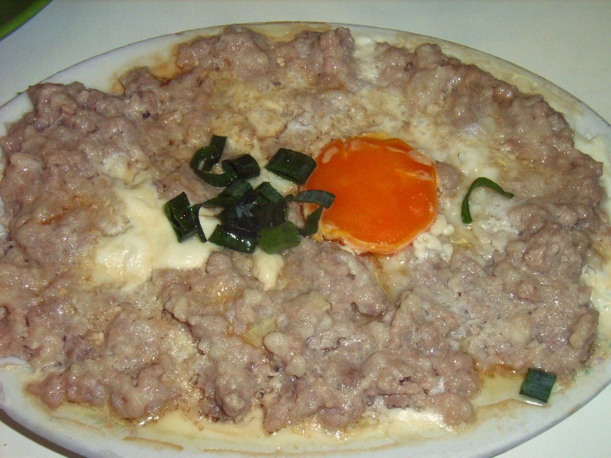 Cantonese steamed pork patty with salted egg yolk and scallions on a plate.