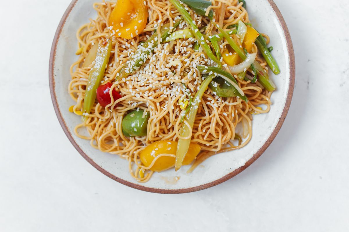 Sesame pepper scallion lo mein with bell peppers, green onions, glossy noodles, and toasted sesame seeds.