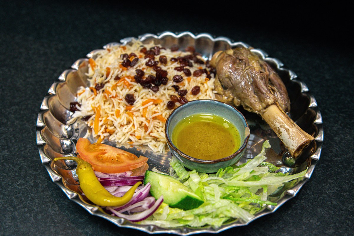 Xinjiang lamb pilaf with rice, lamb, carrots, onions, raisins, and cumin-scented garnish.
